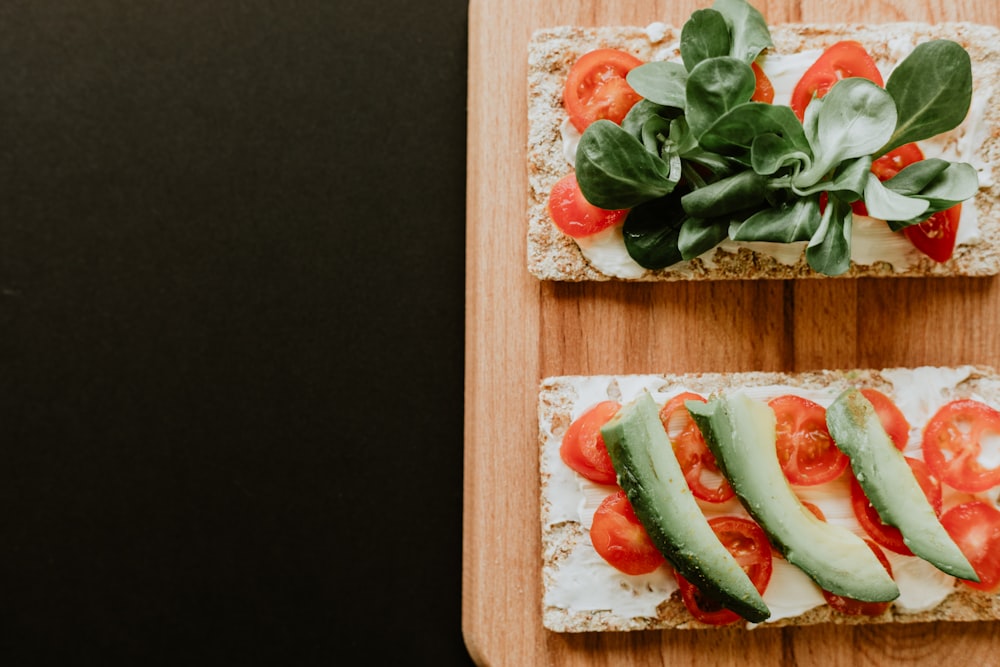 bread with vegetables, sliced tomatoes and spread filling on brown wooden board