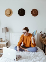 woman sitting on bed facing laptop