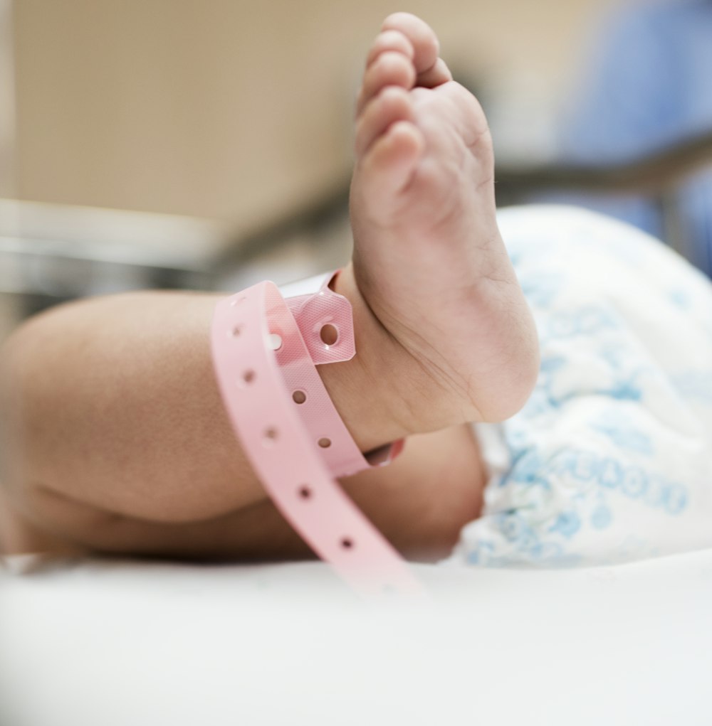 selective focus photography of baby wears pink name tag