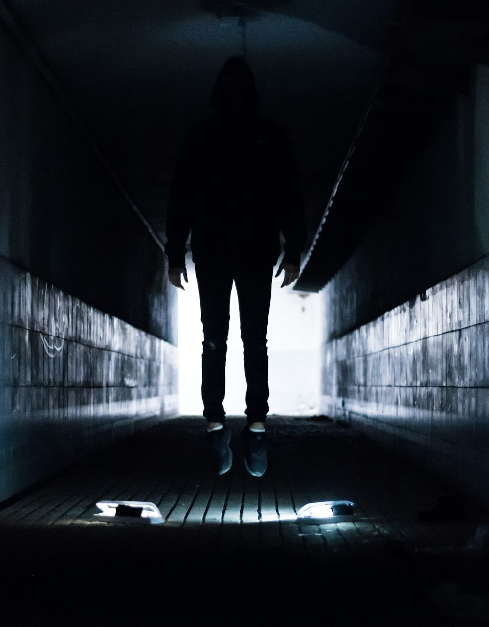 a person standing in a dark tunnel with a skateboard