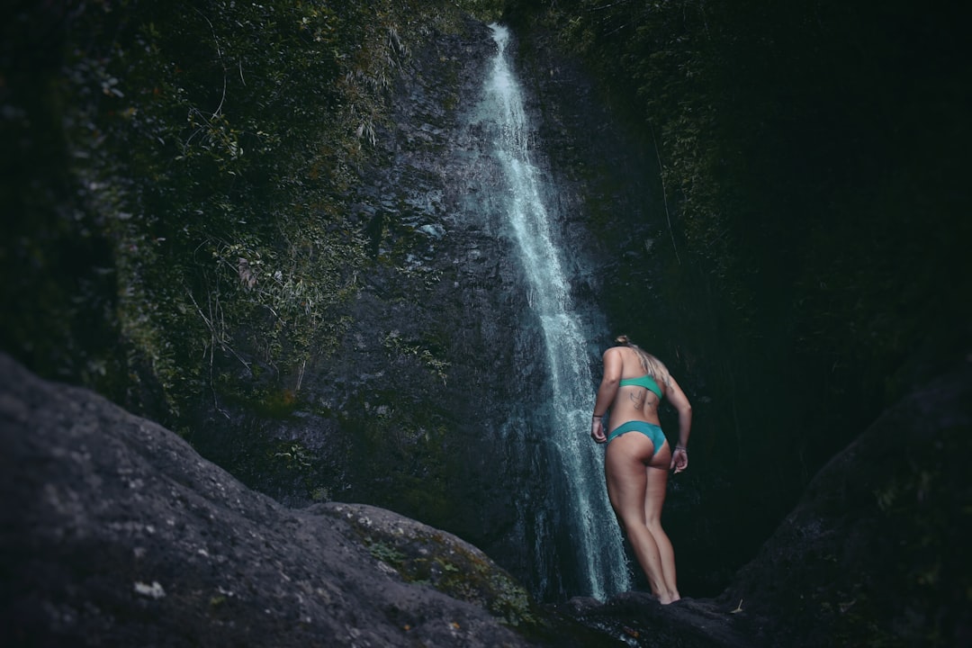 woman standing below waterfalls