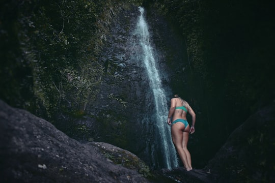 woman standing below waterfalls in Mānoa United States
