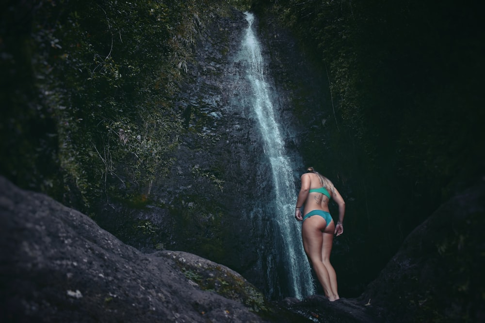 woman standing below waterfalls