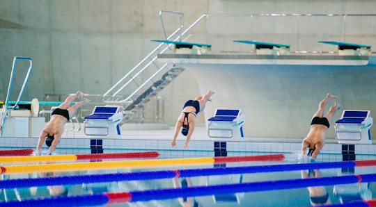 three swimmers jumping on swimming pool in London Aquatics Centre United Kingdom