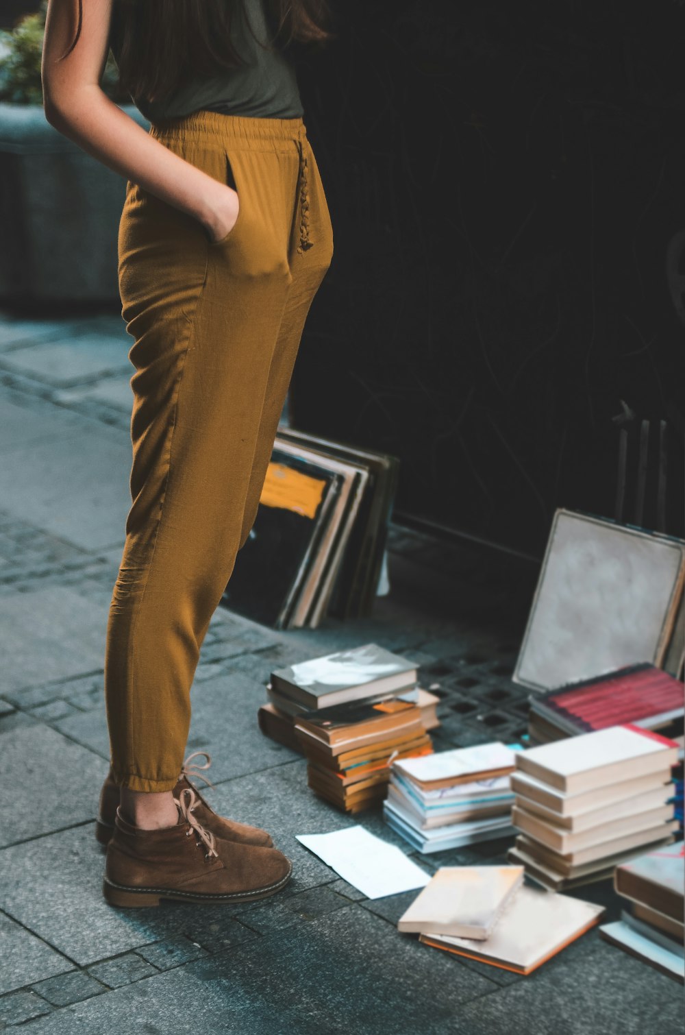 personne portant un pantalon marron à côté d’un lot de livres assortis