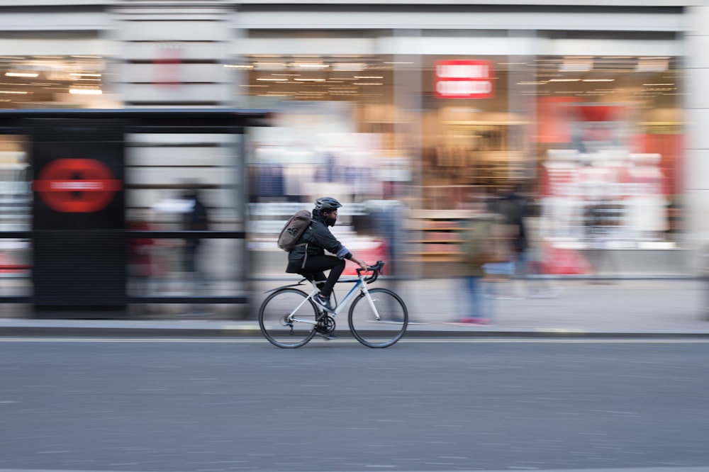 photo en accéléré d’une personne roulant sur un vélo de route blanc