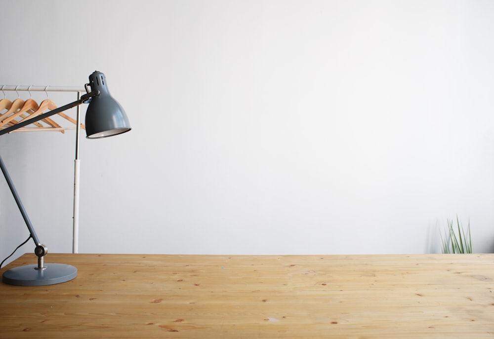 Graue Balanced-Arm-Lampe auf braunem Holztisch