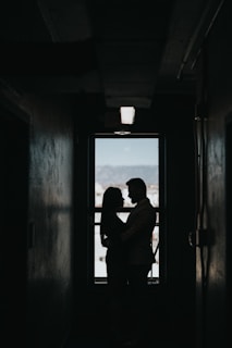 An artistic silhouette of the couple framed by architectural lines and deep shadows.