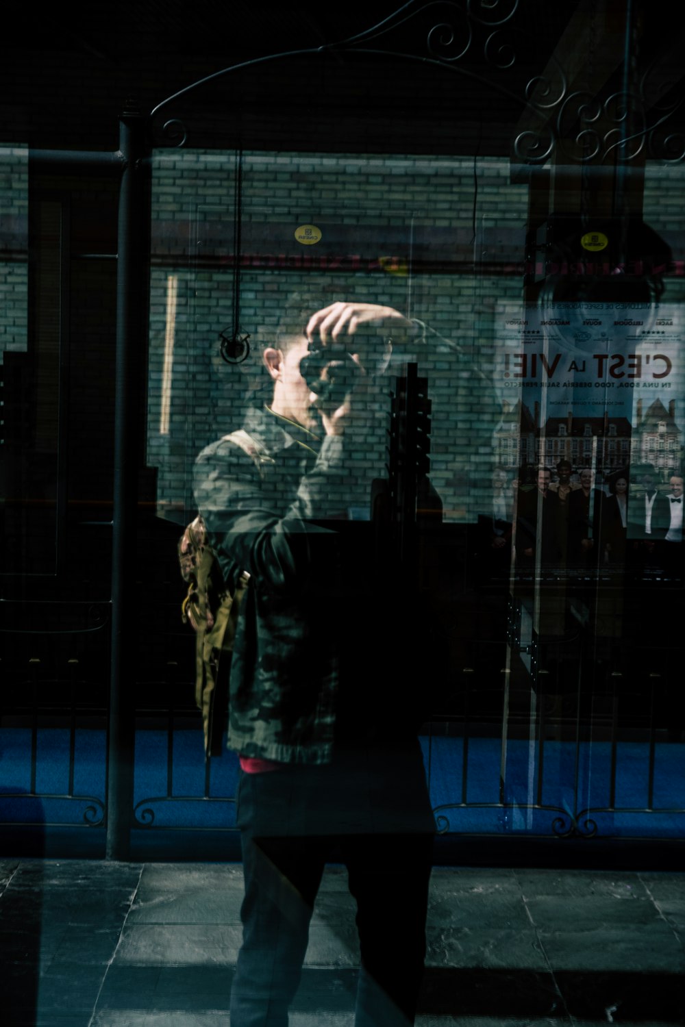 man taking photo himself by reflecting on glass wall