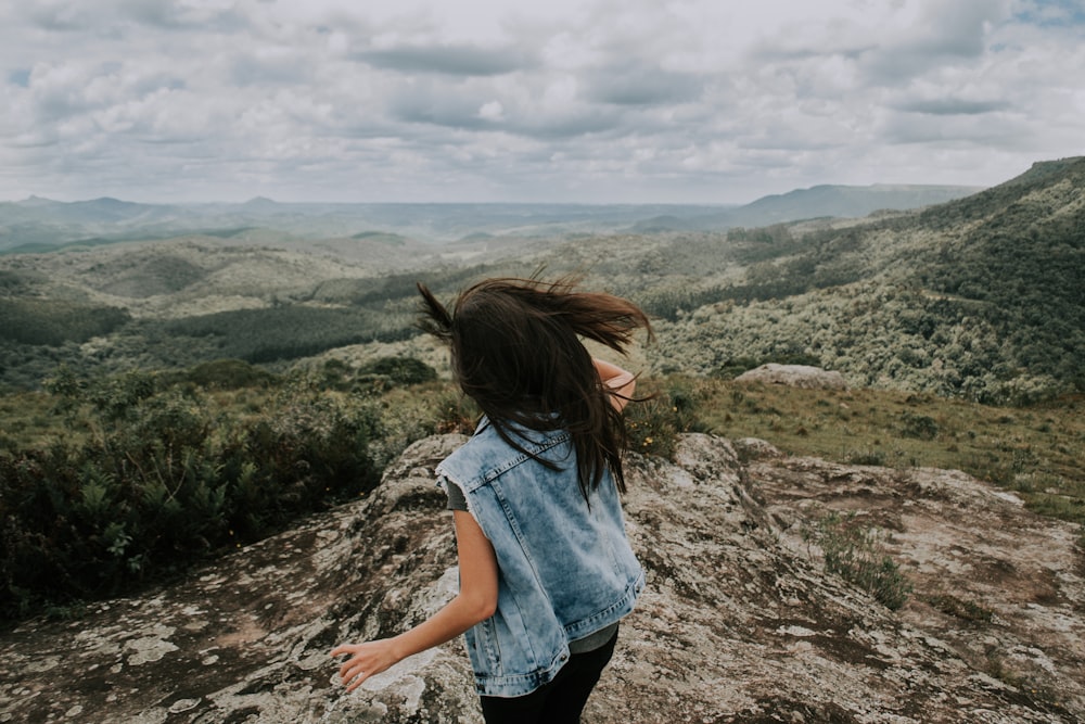 woman wearing blue denim jacket standing on the cliff