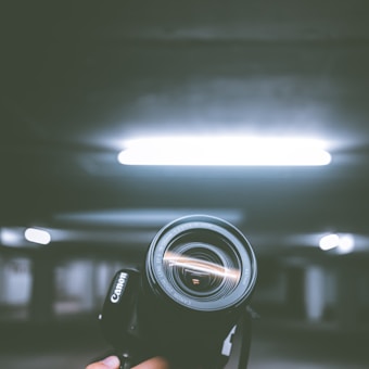 person holding black Canon DSLR camera inside indoor vehicle garage