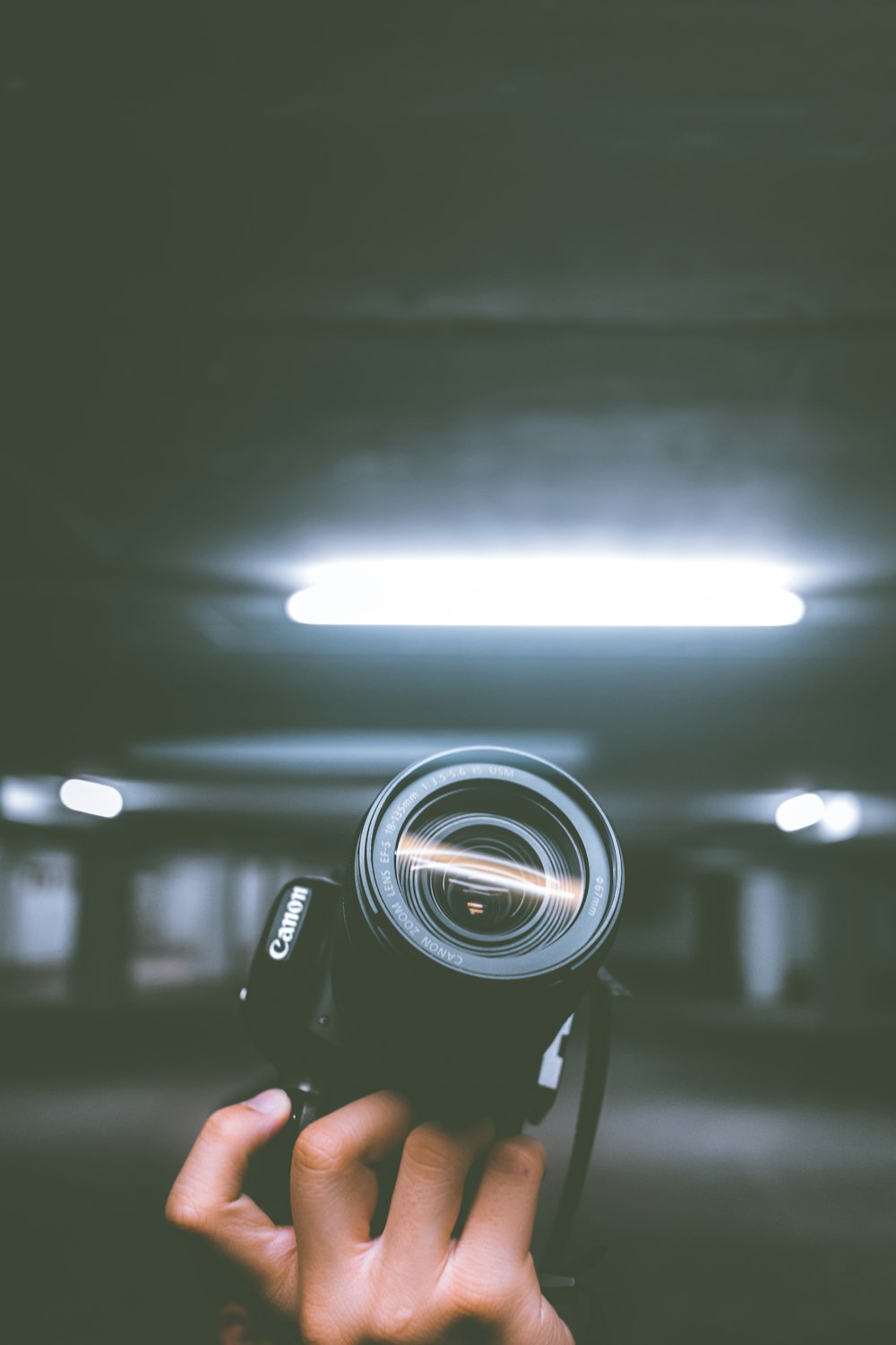 person holding black Canon DSLR camera inside indoor vehicle garage