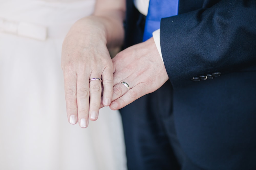 A portrait of a couple embracing each other while wearing rings on their left hands.