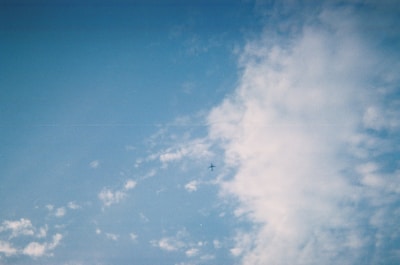 A modern airplane flying above the clouds during a clear blue sky.