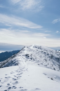 Snow-capped alpine ridge under a clear blue sky, with hikers in the distance.