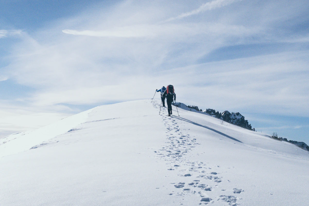 Two climbers ascending a snow-covered mountain ridge