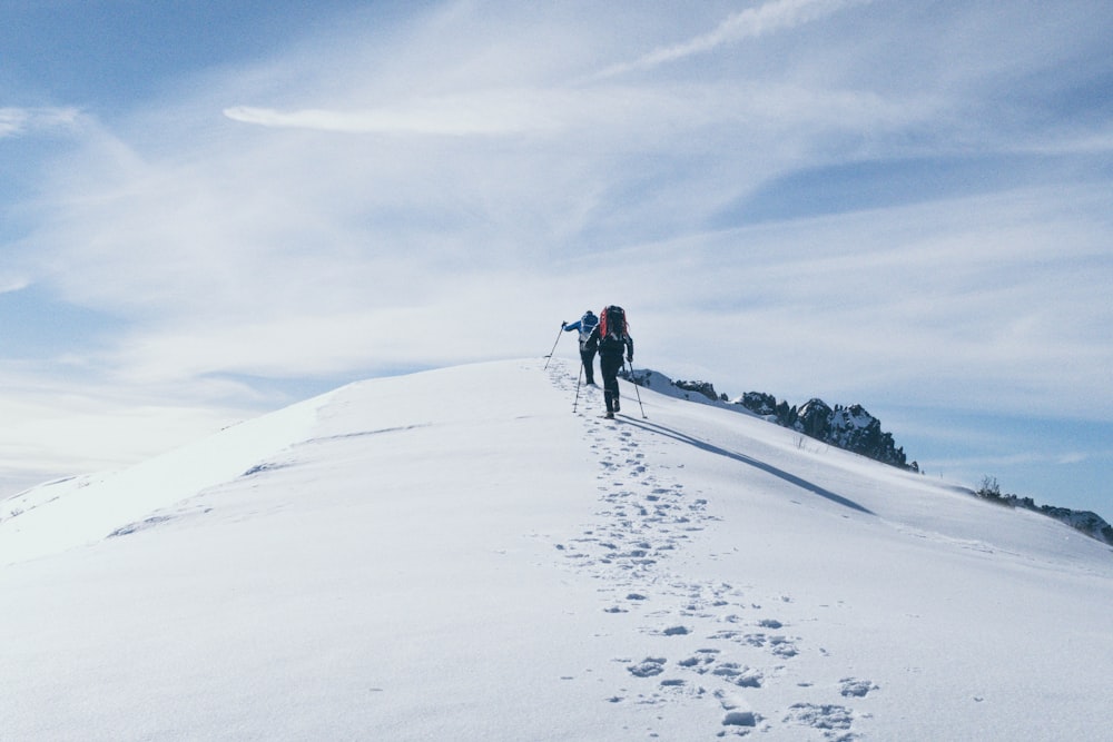 two person climbing on mountain covered snow