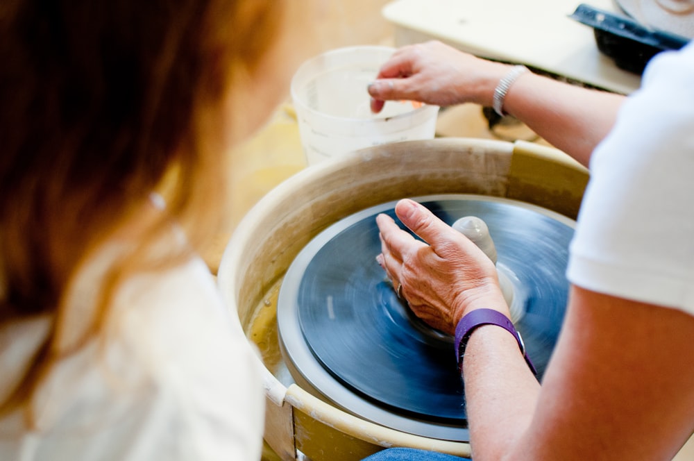 a woman is spinning a bowl on a potter's wheel