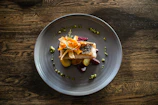 A colorful plate of pește (fish) with lemon wedges and fresh herbs, presented on a wooden table.