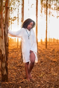 A serene woman standing barefoot in a sunlit forest, embracing nature and peace.