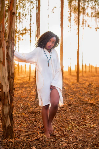 A serene woman smiling peacefully while walking barefoot in a sunlit forest, embodying calm and healing.