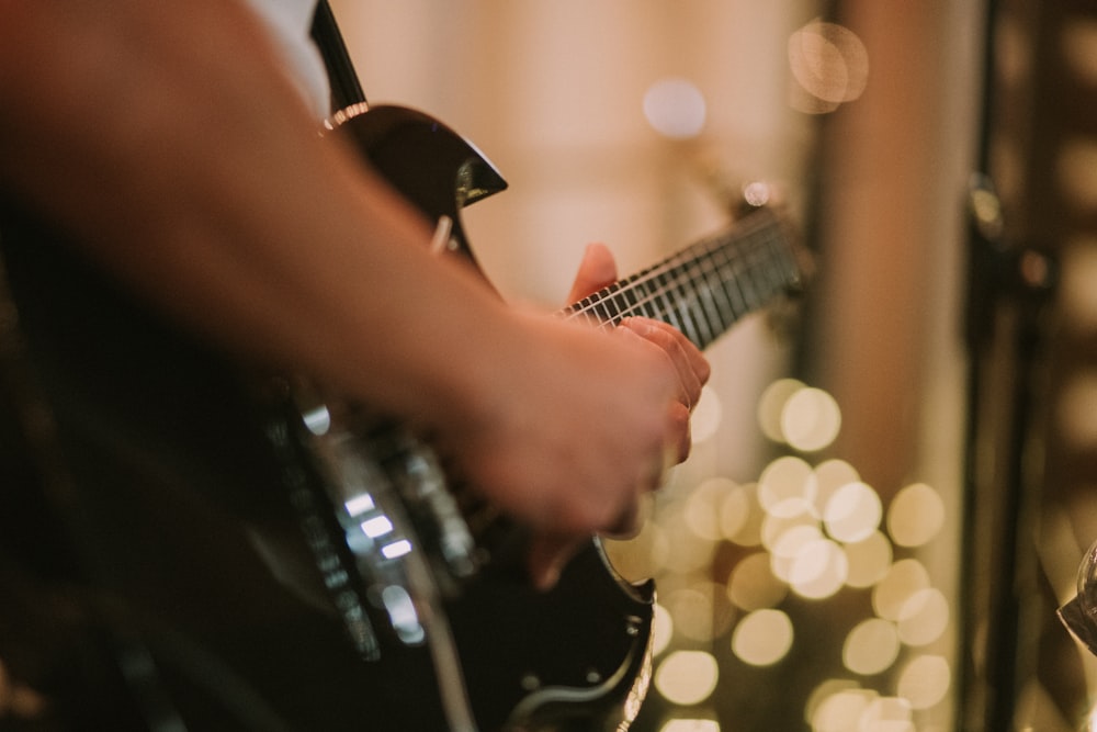 person playing black SG guitar