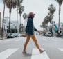 man wearing red cap crossing street