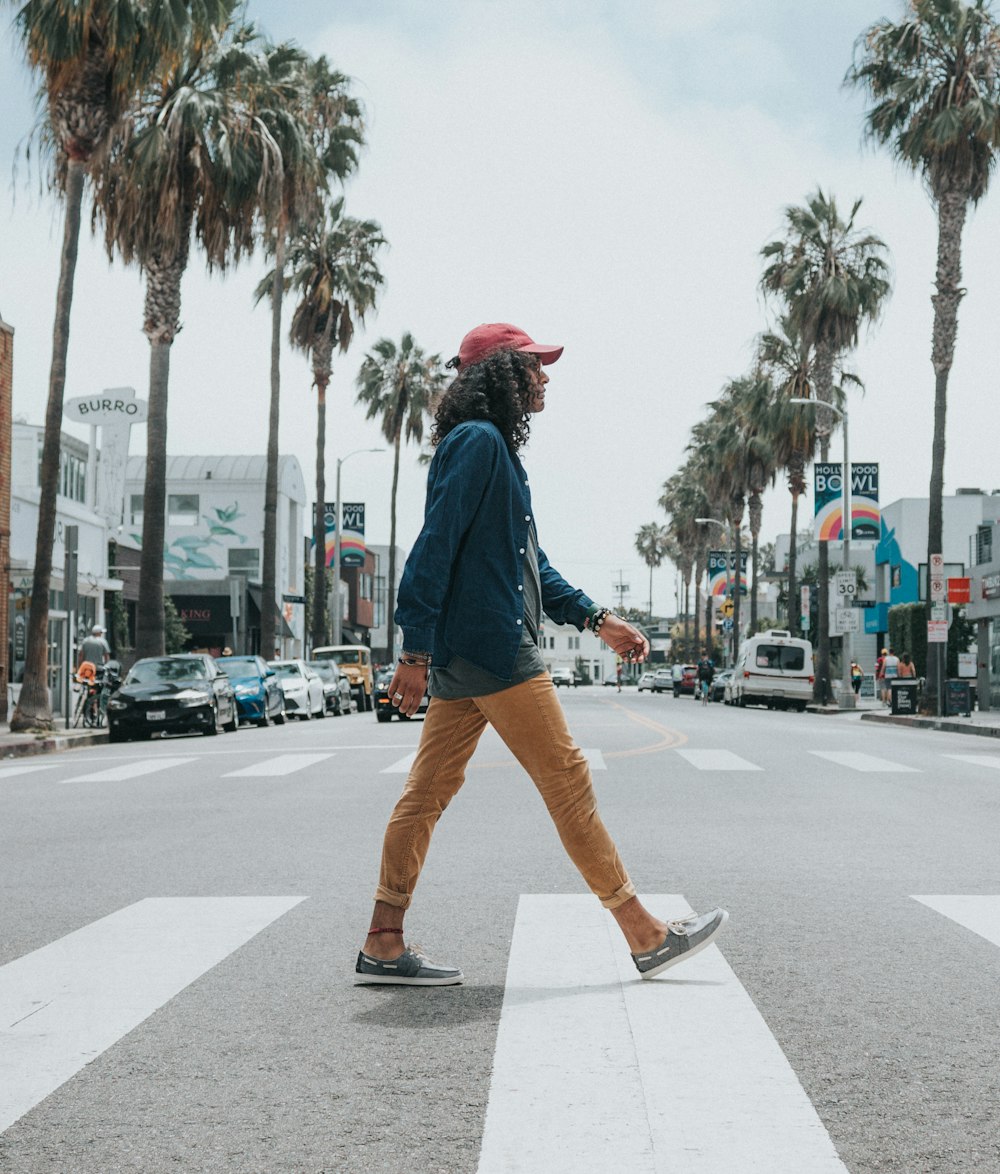 man wearing red cap crossing street