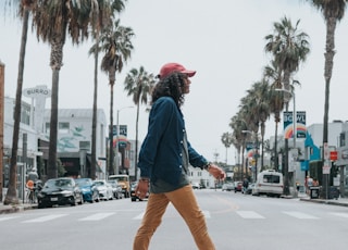man wearing red cap crossing street