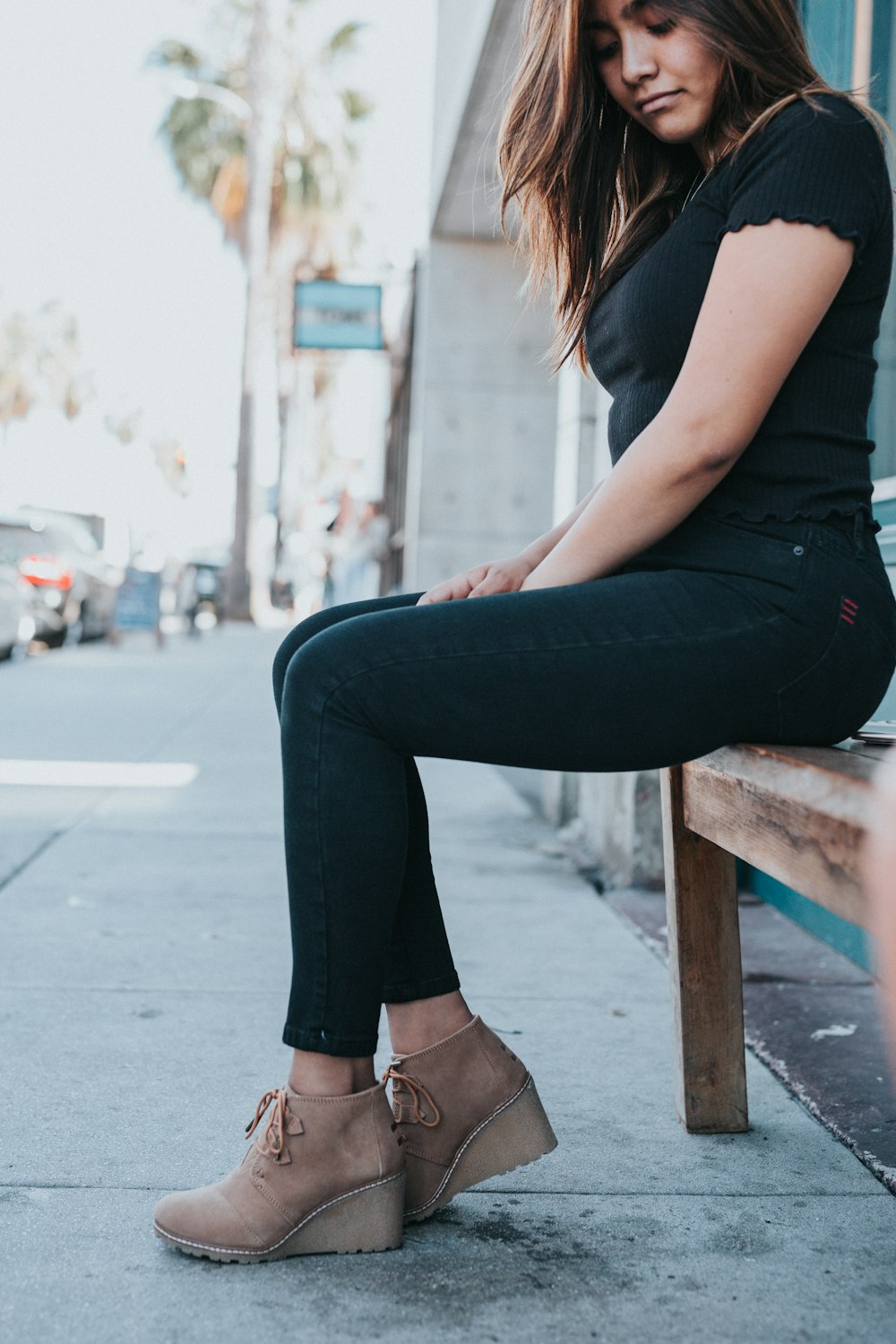 woman in black t-shirt and black pants sitting on brown wooden bench during daytime