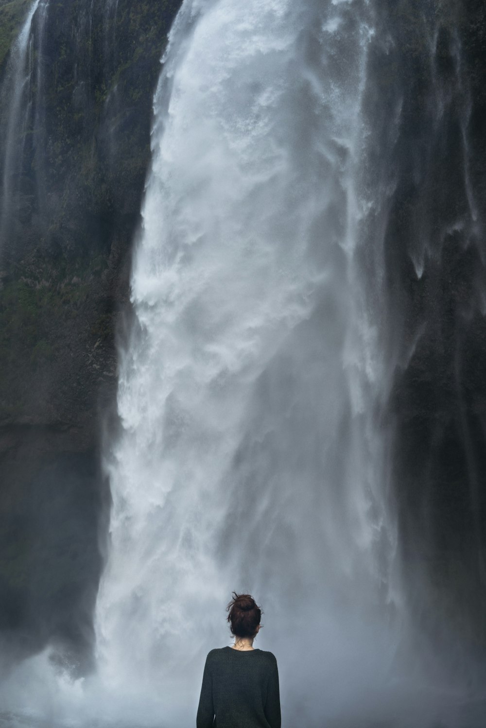 woman in black long-sleeved shirt standing near falls