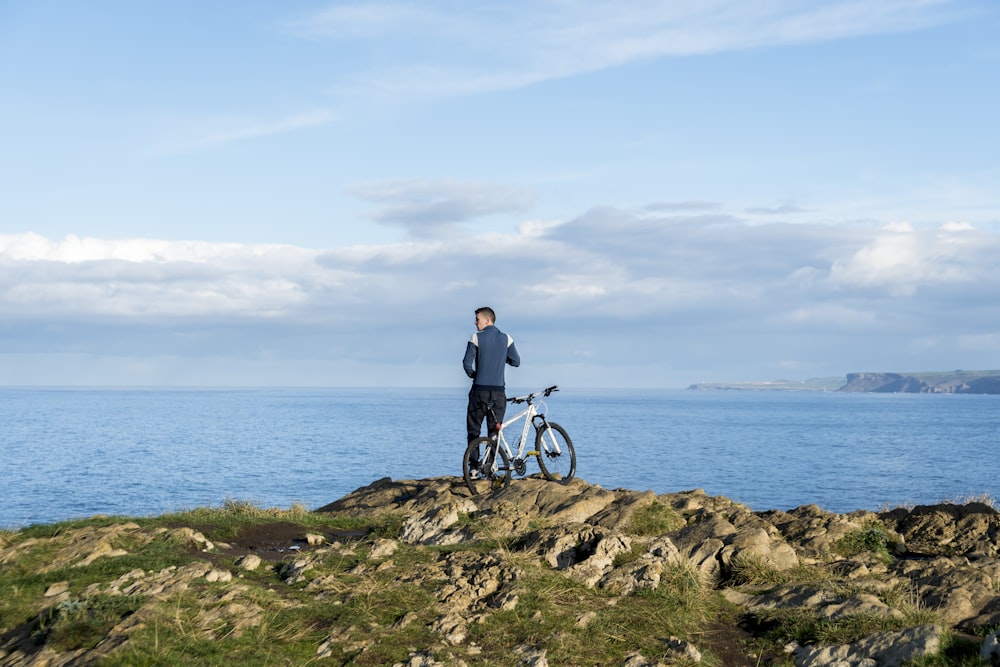 a man standing next to a bike on top of a hill