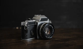 A sleek black-and-white photo of a vintage film camera on a tripod against a minimalist backdrop