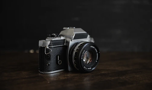 A sleek black-and-white photo of a vintage film camera on a tripod against a minimalist backdrop