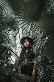woman standing surrounded by palm leaves