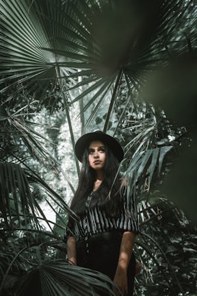 woman standing surrounded by palm leaves