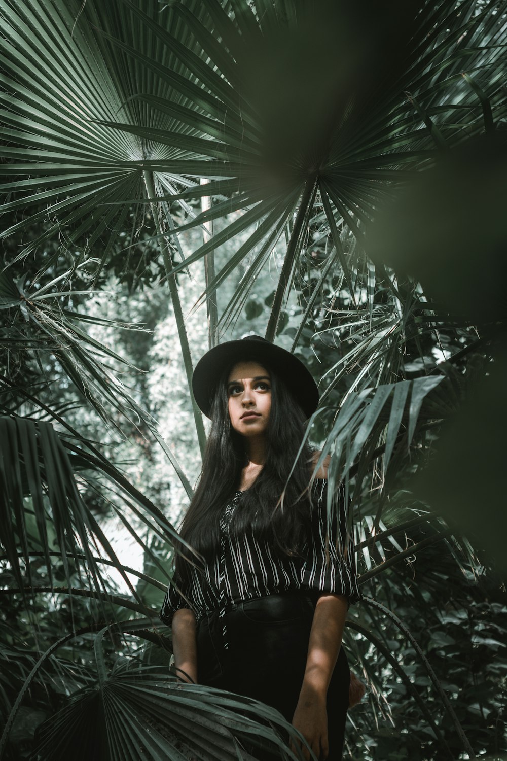 woman standing surrounded by palm leaves