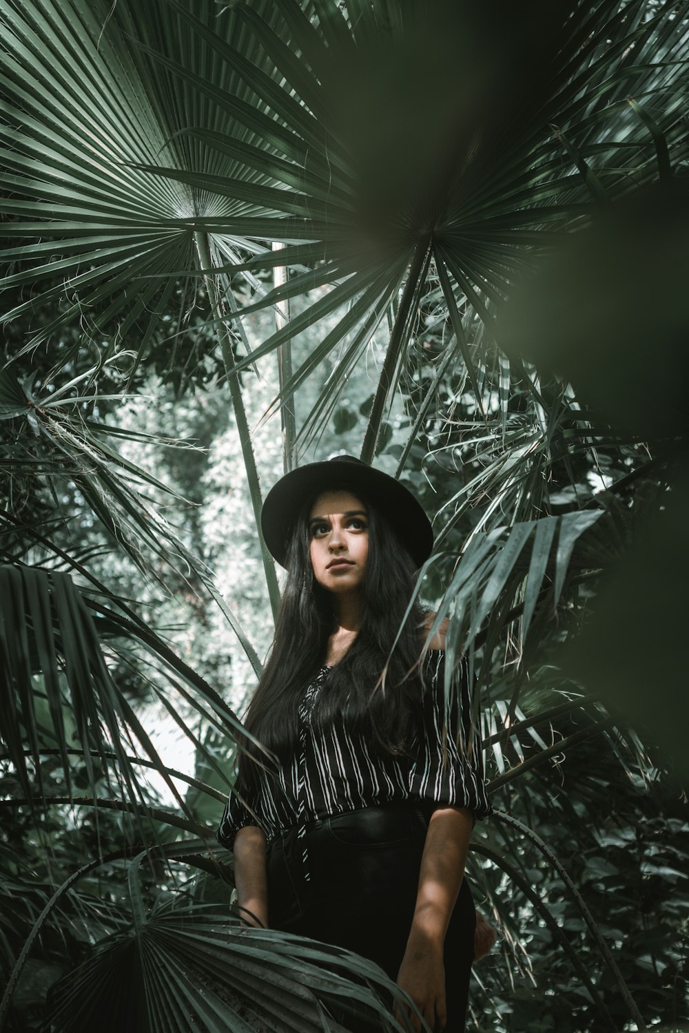 Frau steht umgeben von Palmblättern