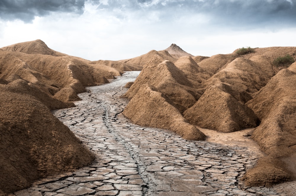 gray dry soil between brown mountains under white clouds