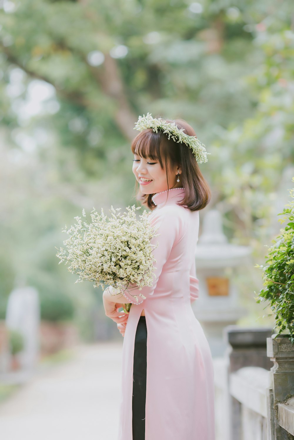 femme souriant tout en portant un bouquet de fleurs