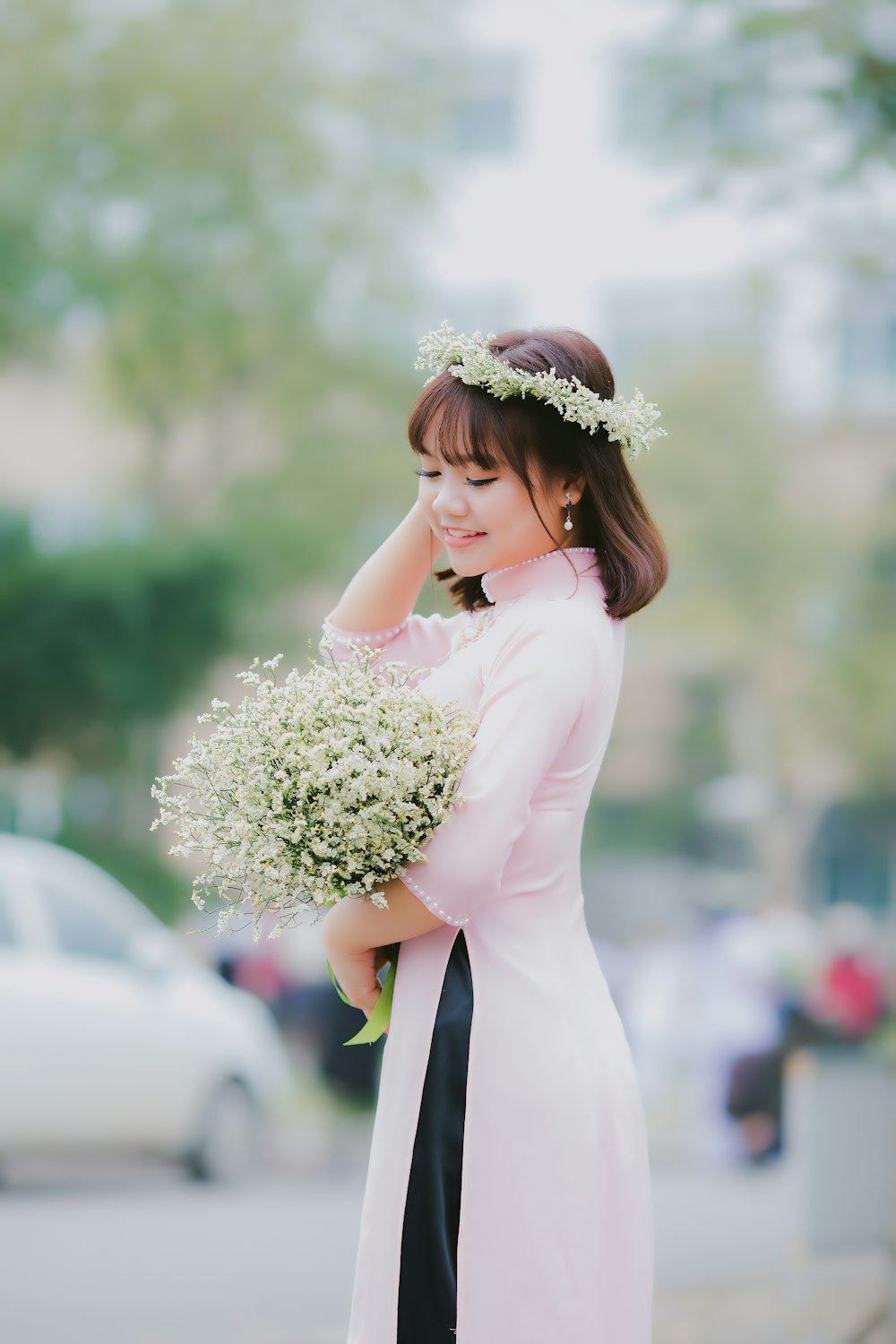 Frau hält ihr Haar, während sie einen weißblättrigen Blumenstrauß in der Fokusfotografie trägt