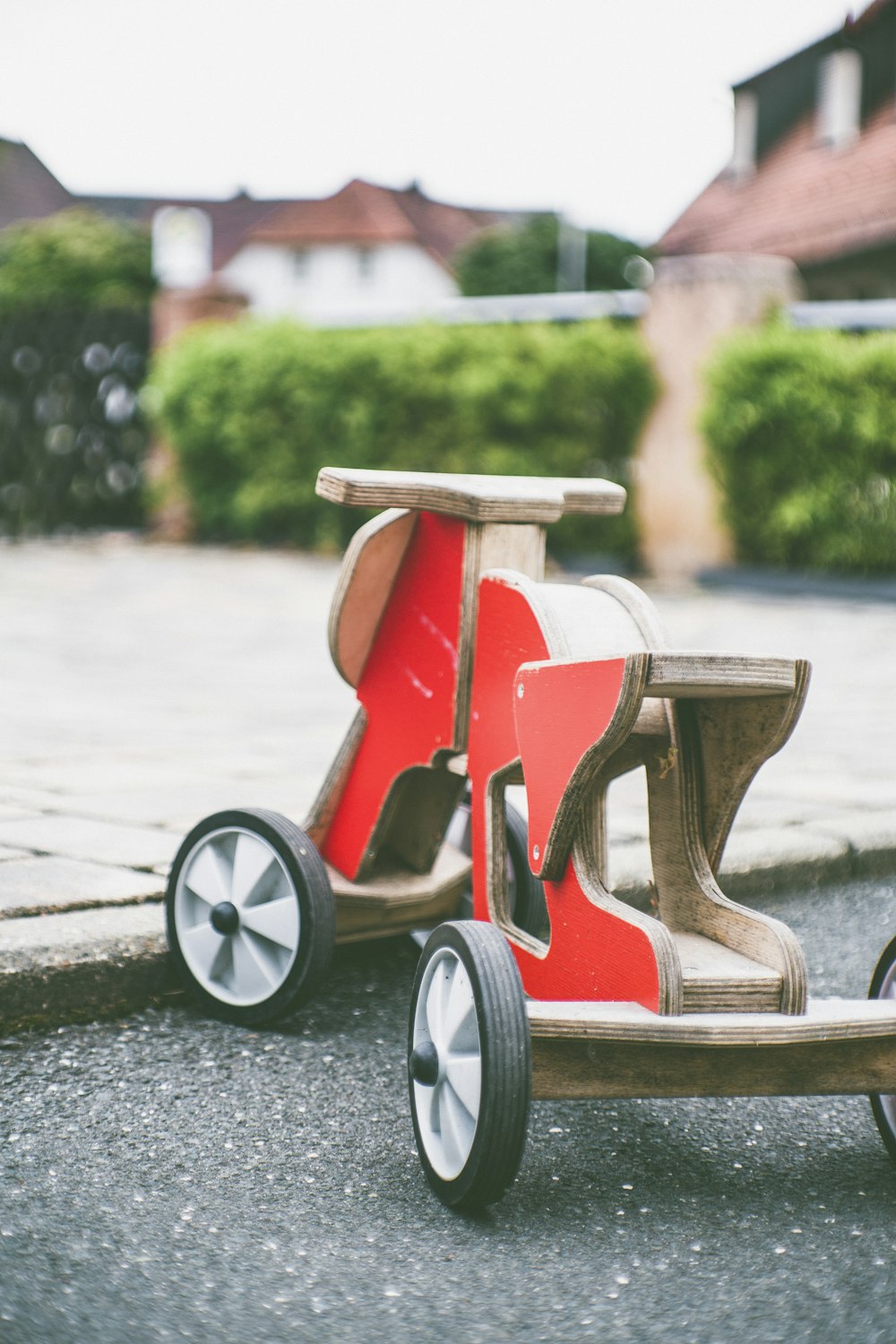 toddler's red and brown wooden ride-on toy on concrete pavement