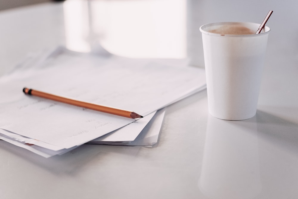 white disposable cup and papers