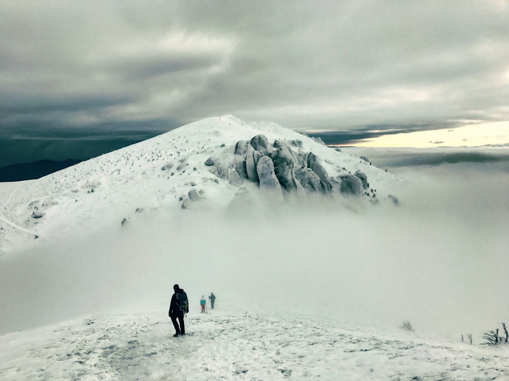 three person standing on the snowy field