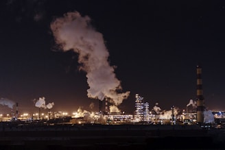 city factories with grey smoke during nighttime