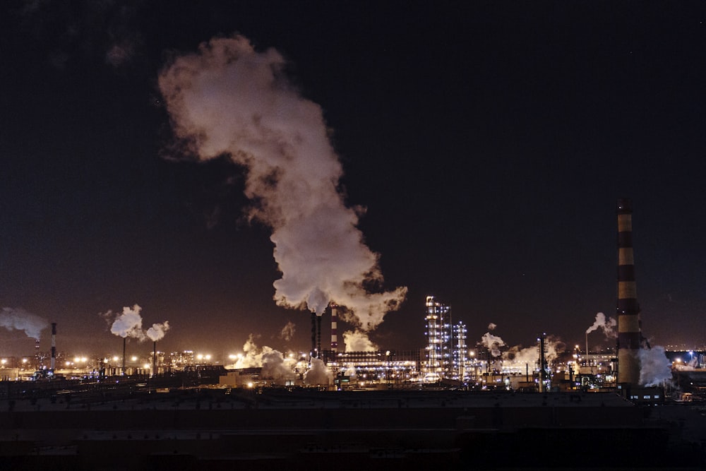 city factories with grey smoke during nighttime