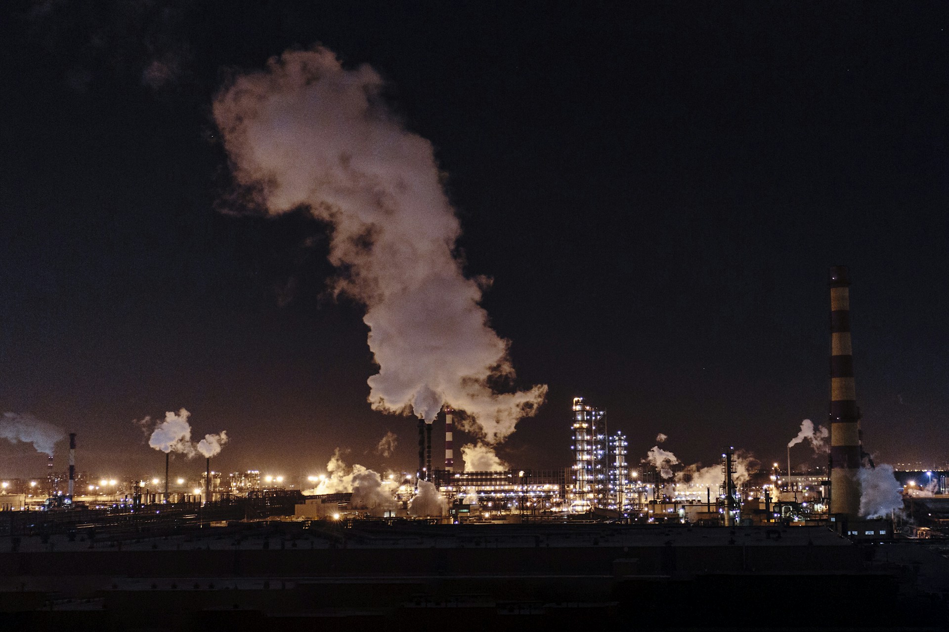 city factories with grey smoke during nighttime