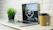 A cozy workspace with a laptop, coffee cup, and potted plant inviting a message.