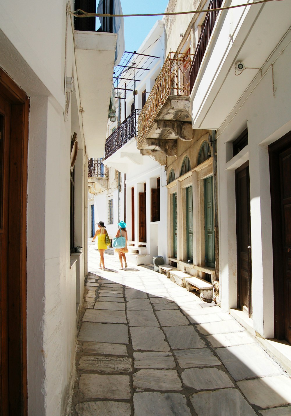 two women walking in between of buildings taken at daytime