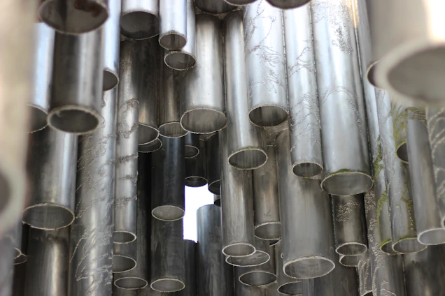 Close-up of stacked steel pipes gleaming under industrial lighting in a modern warehouse.